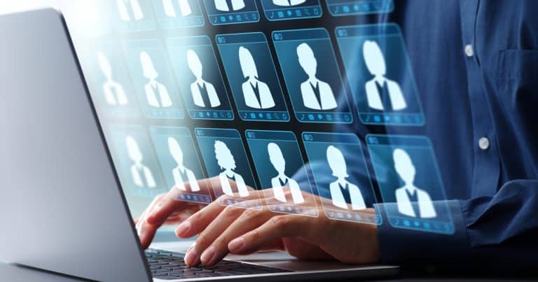 Person typing on a laptop with virtual profiles displayed, representing digital character-based hiring.